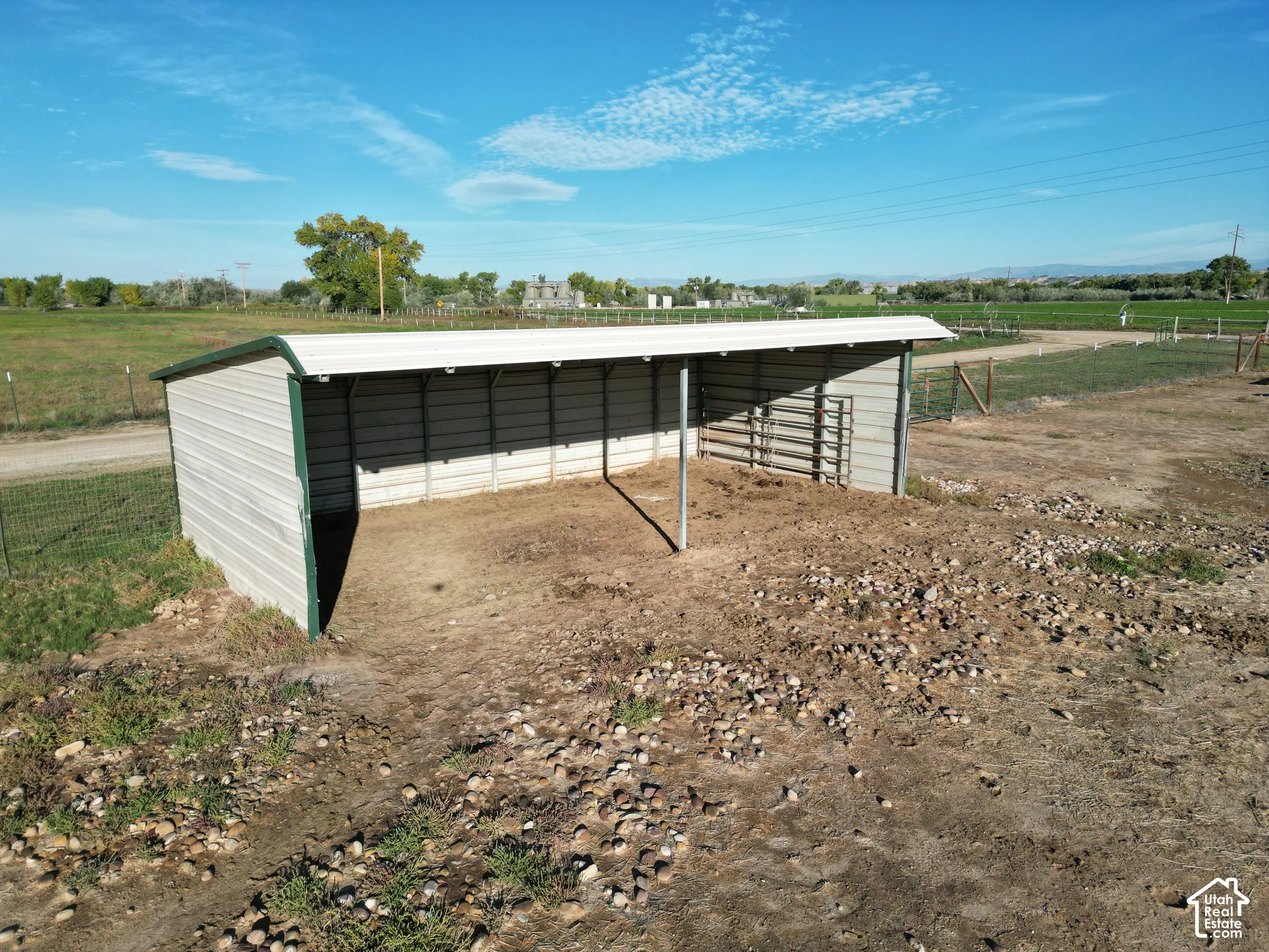 Metal shelter with open-sided design, metal roofing, and a fenced enclosure