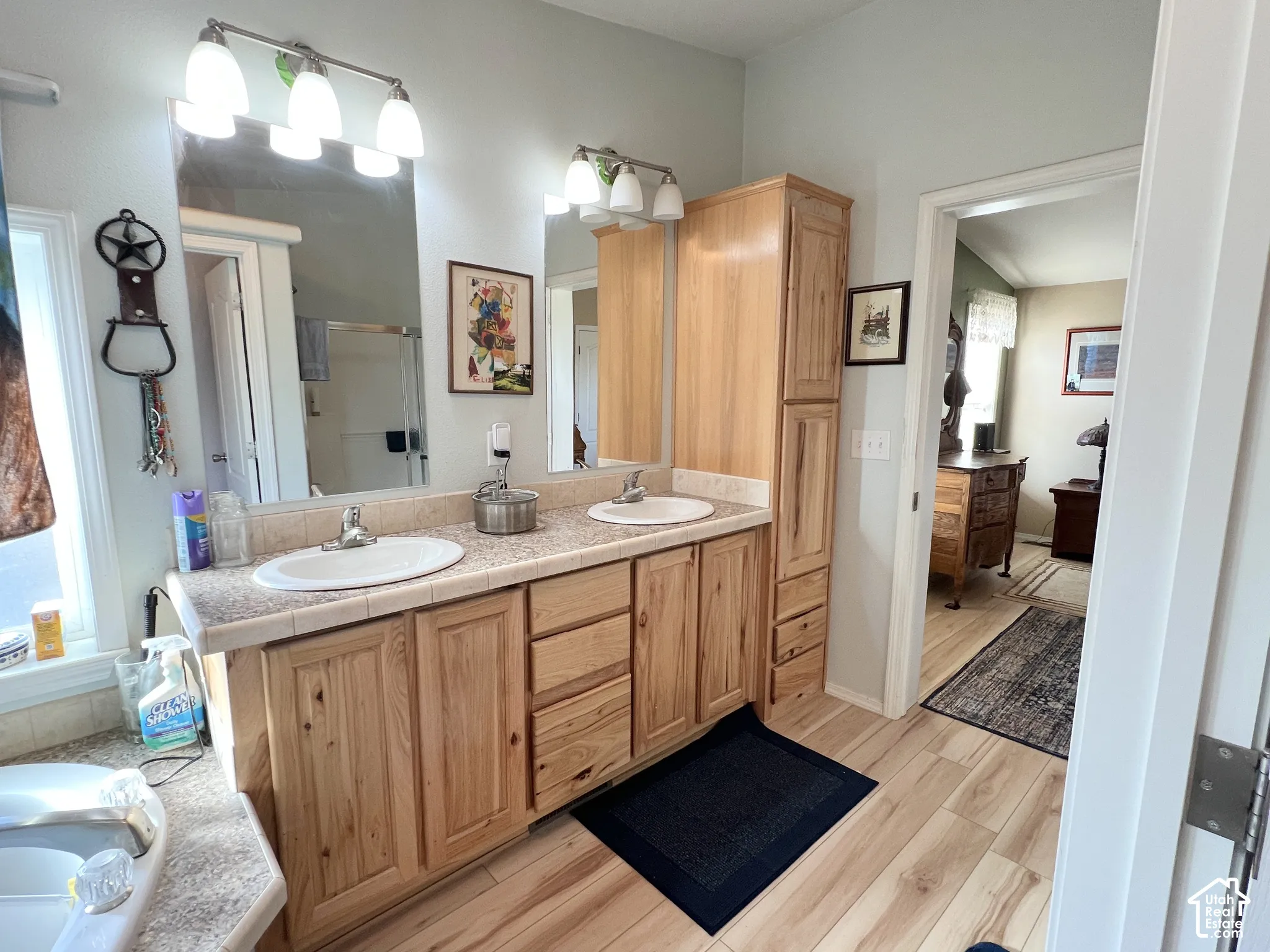Dual sink vanity with light wood cabinetry, tiled countertop, and wood-finish flooring