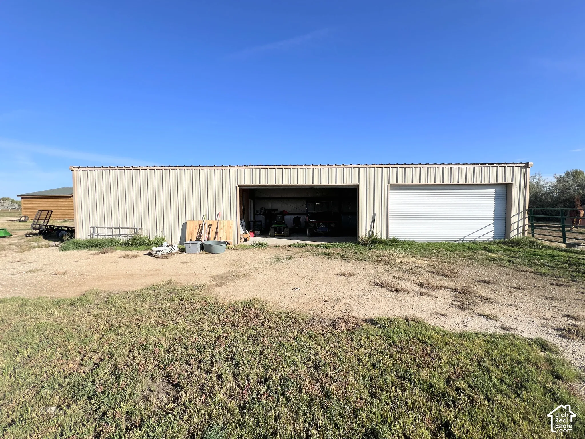 Metal utility building featuring two large bay doors, one open and one with a roll-up door