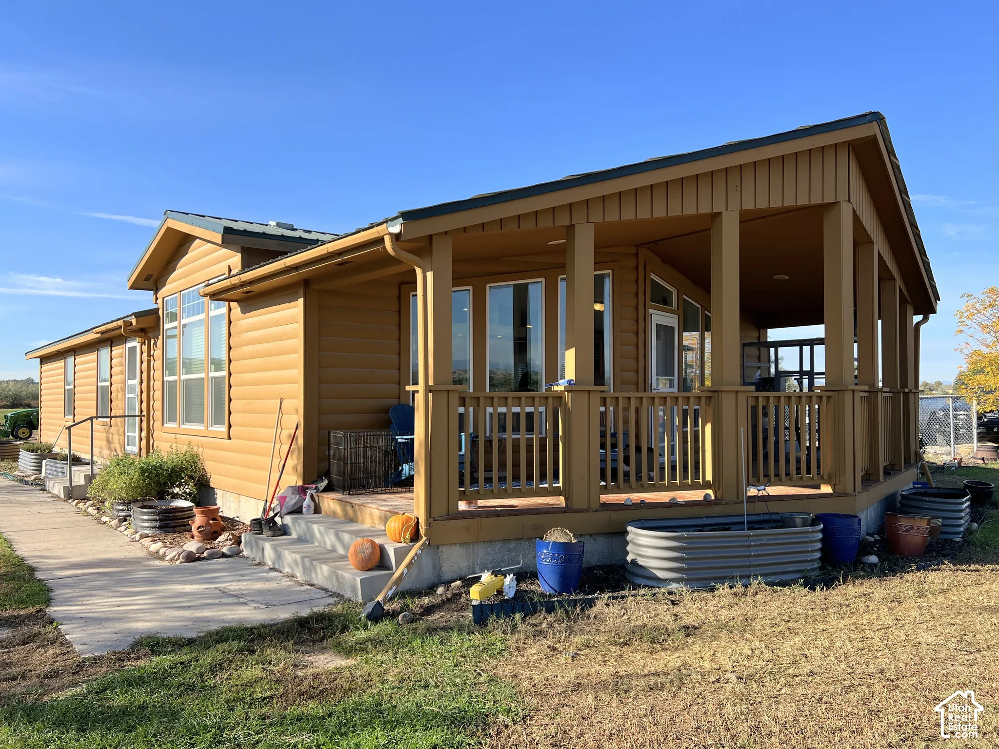 Expansive covered porch with wood railing and columns, horizontal siding, and multiple windows