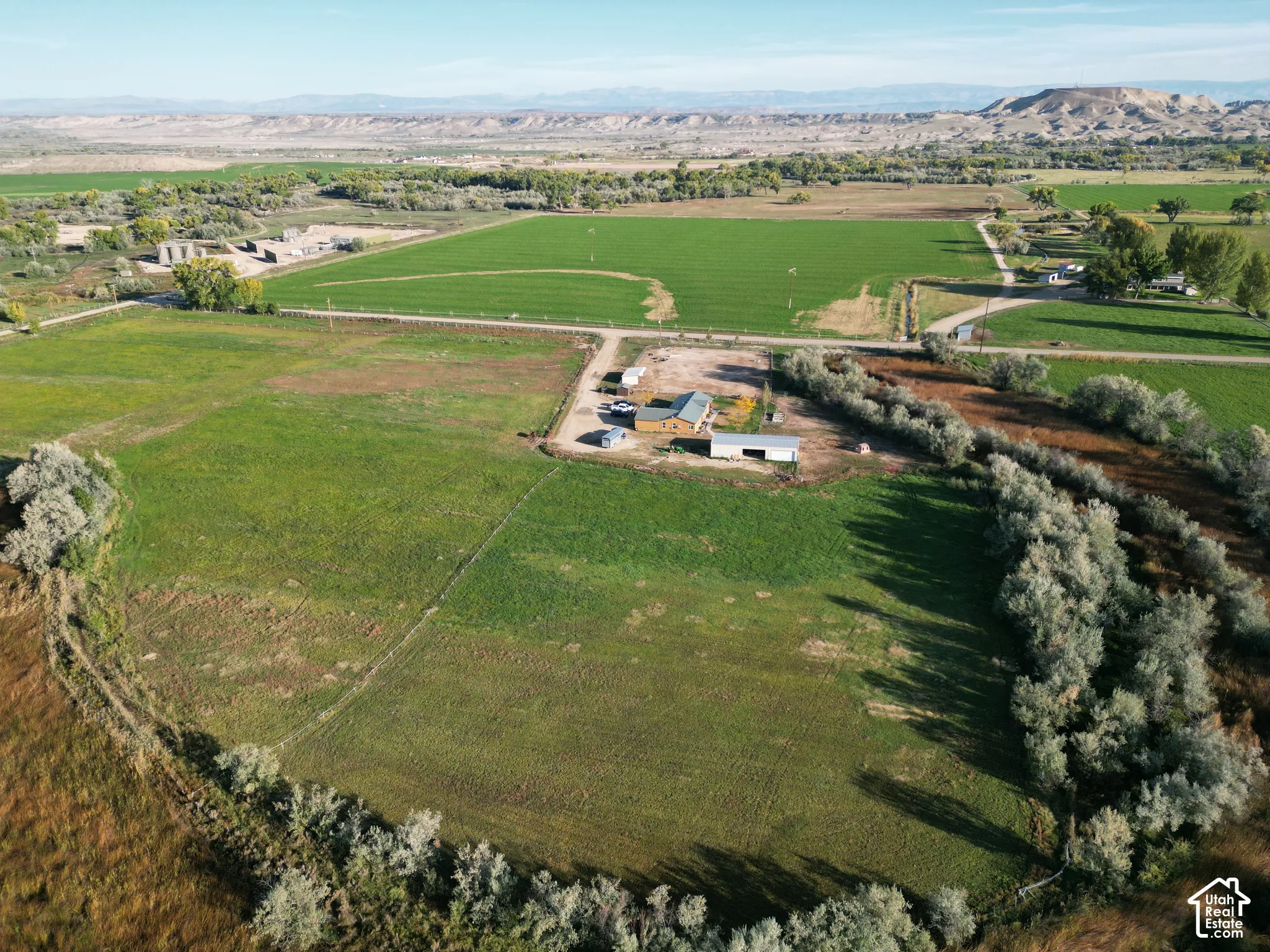 Expansive agricultural land featuring cultivated fields, a detached residence, and multiple outbuildings