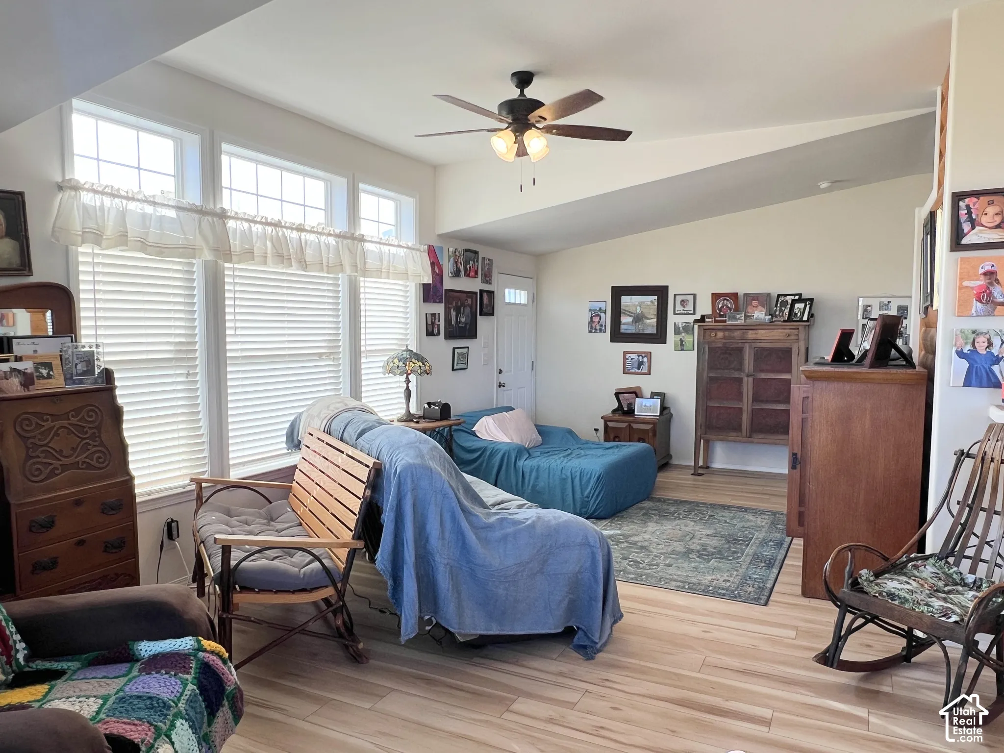 Vaulted ceiling with a ceiling fan, wood-finish flooring, and multiple windows with transoms