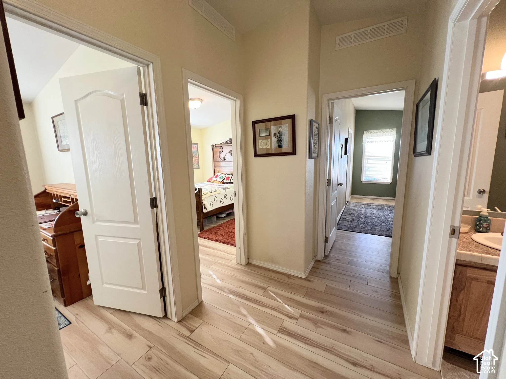Wood-finish flooring throughout the hallway, leading to rooms with individual door access