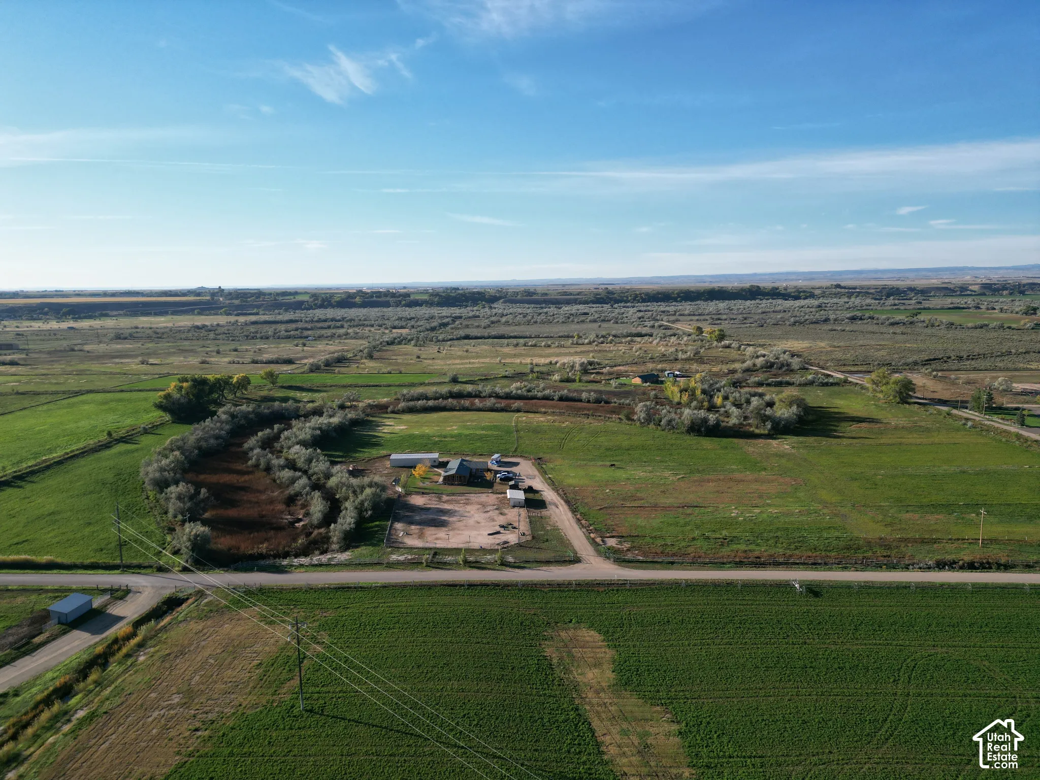 Expansive rural property with multiple structures, surrounded by agricultural fields and natural foliage