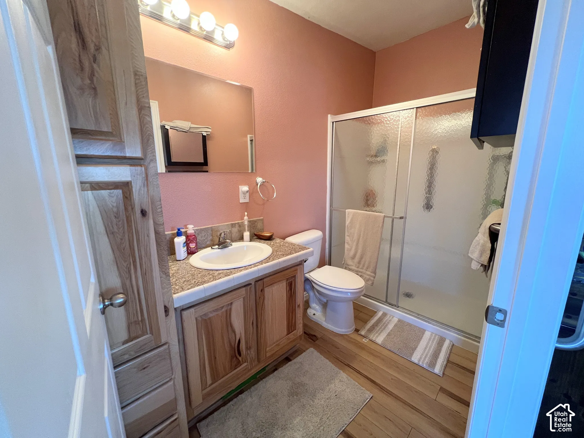 Bathroom featuring a single vanity with wood-finish cabinetry, a white basin sink, and a framed mirror