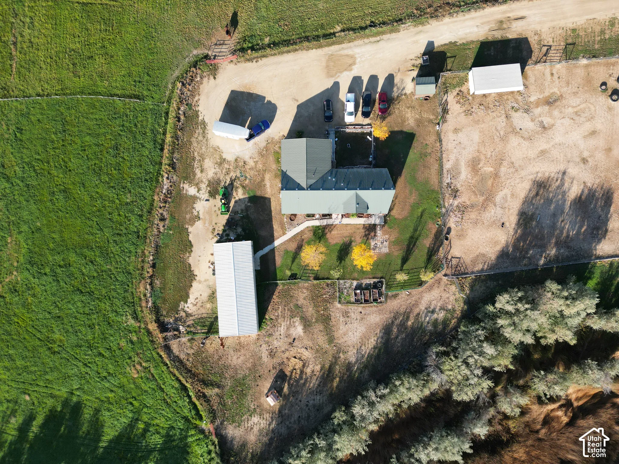 Property featuring a main residence with a green roof, multiple outbuildings, expansive land, and mature trees