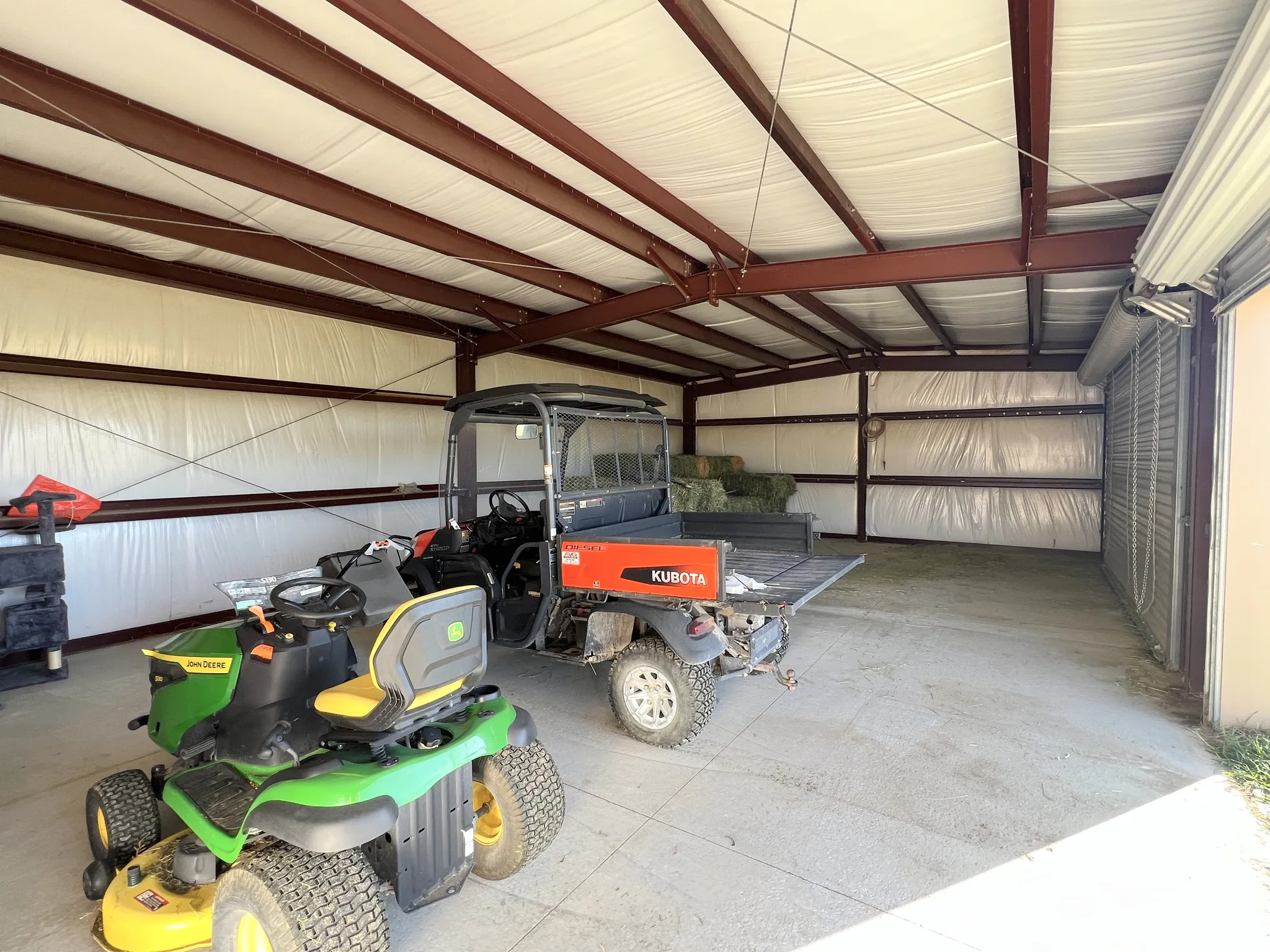 Spacious metal-framed structure with a concrete floor, insulated walls, and a roll-up door
