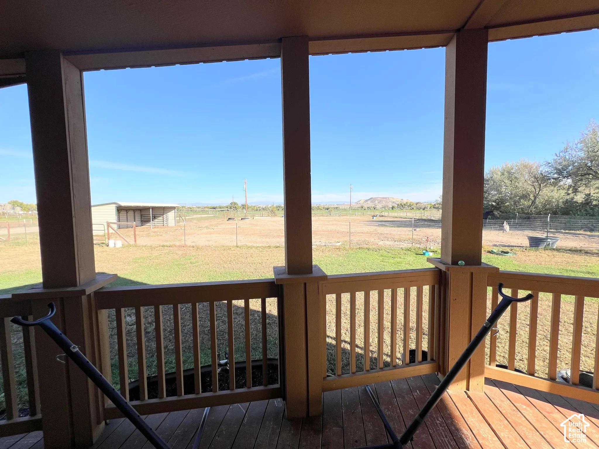 Expansive covered patio with wood flooring, full-height support columns, and wood railings
