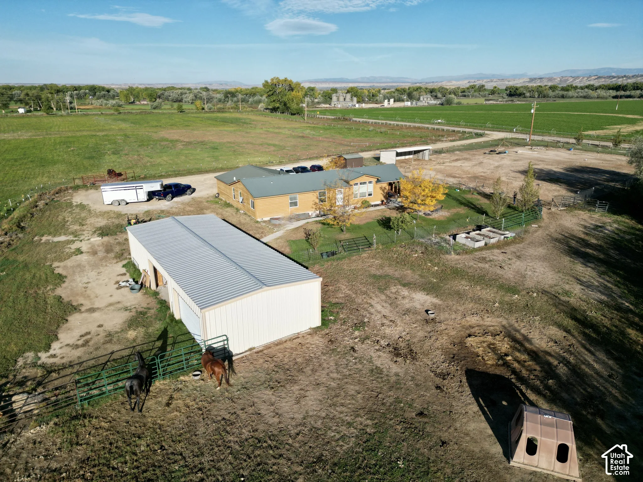 Expansive property featuring a single-story residence, a large detached utility building, fenced pasture areas, and surrounding agricultural land