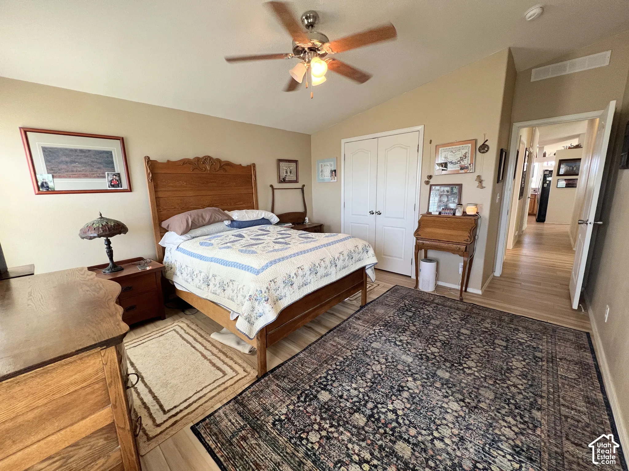 Vaulted ceiling with a ceiling fan, wood-finish flooring, and double-door closet