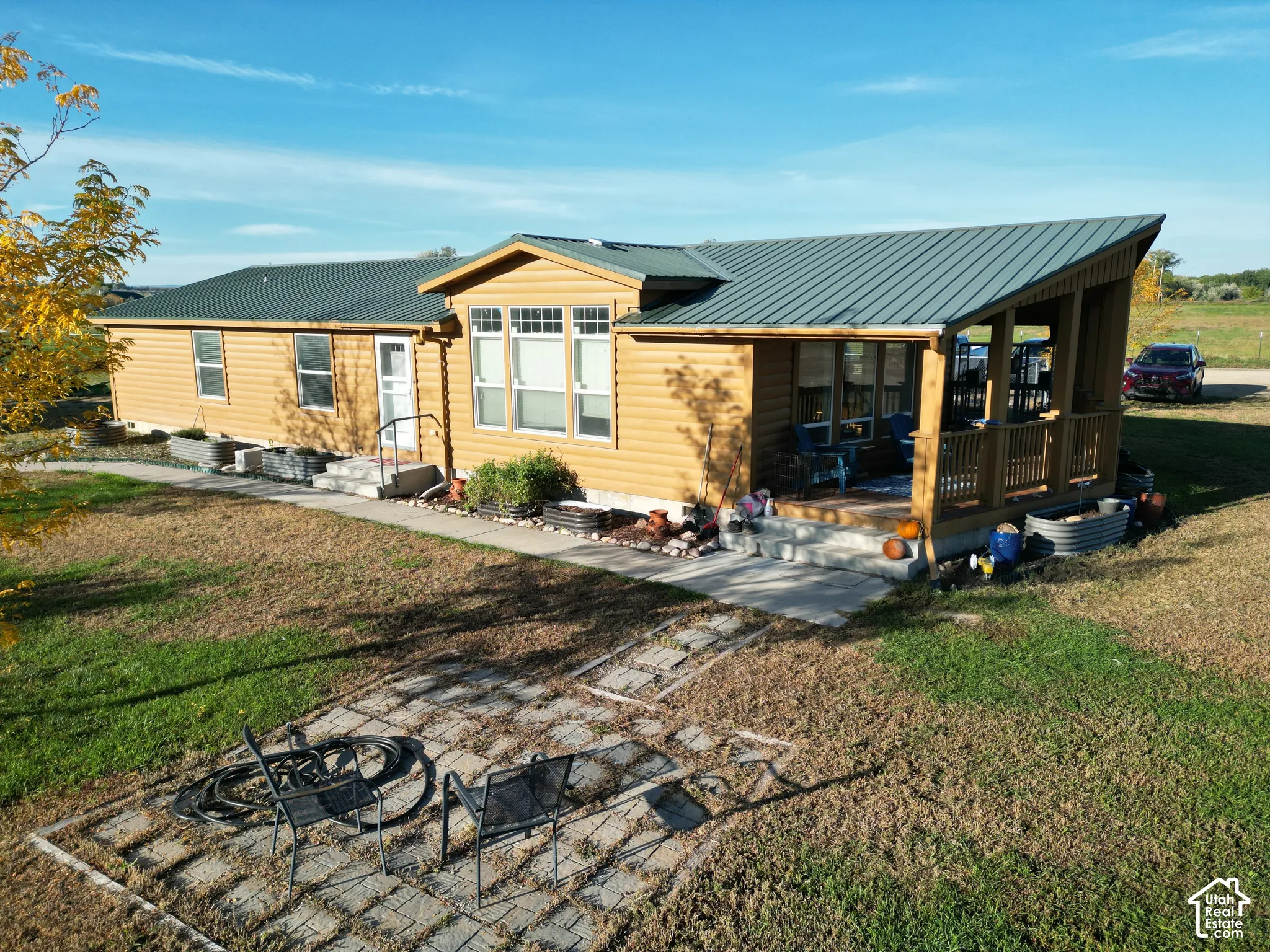Exterior featuring wood-look siding, a covered porch with wood railings, a dark metal roof, and multiple windows