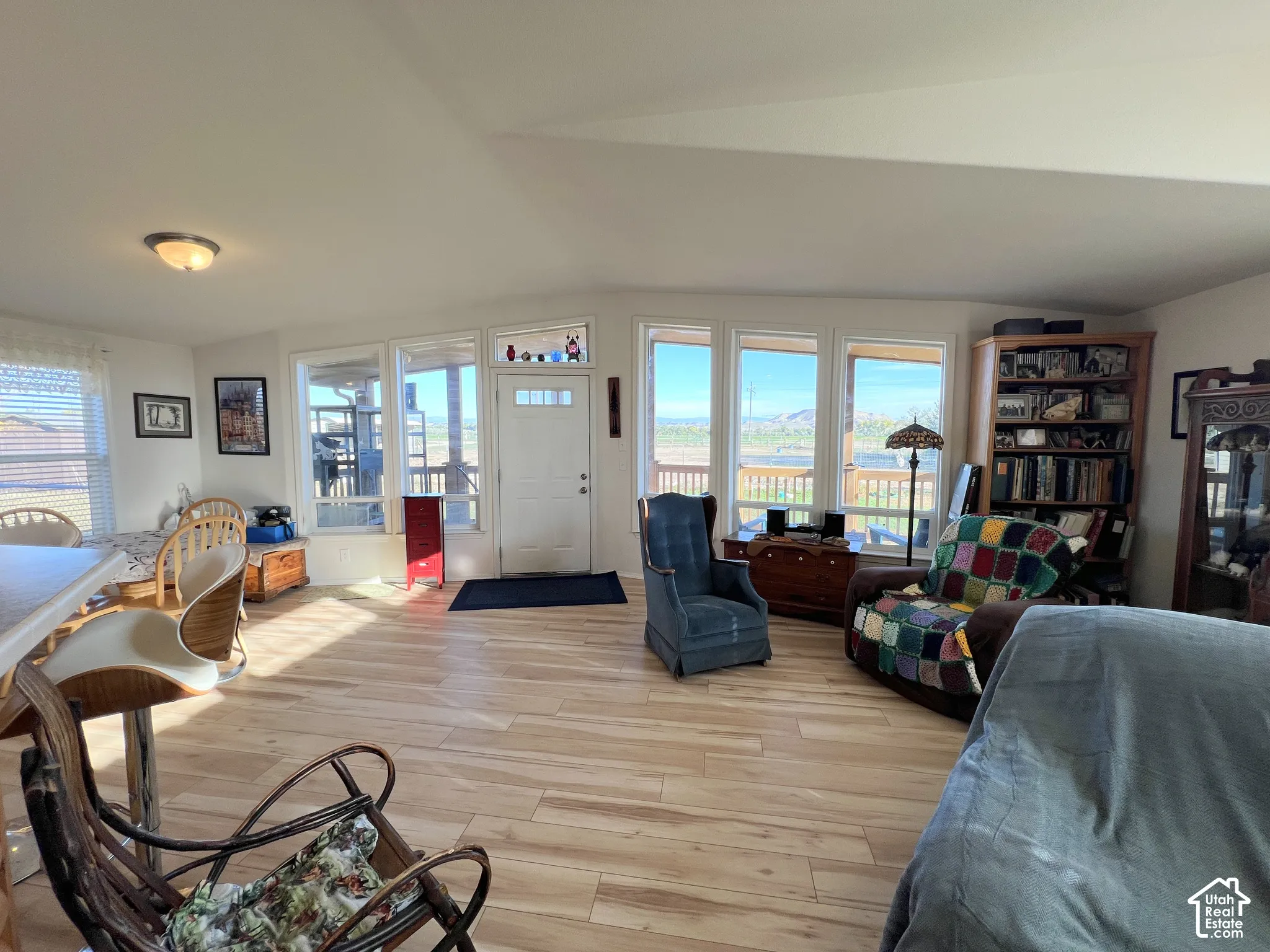 Light wood-finish flooring throughout, bright white walls, and a white front entry door with glass inserts