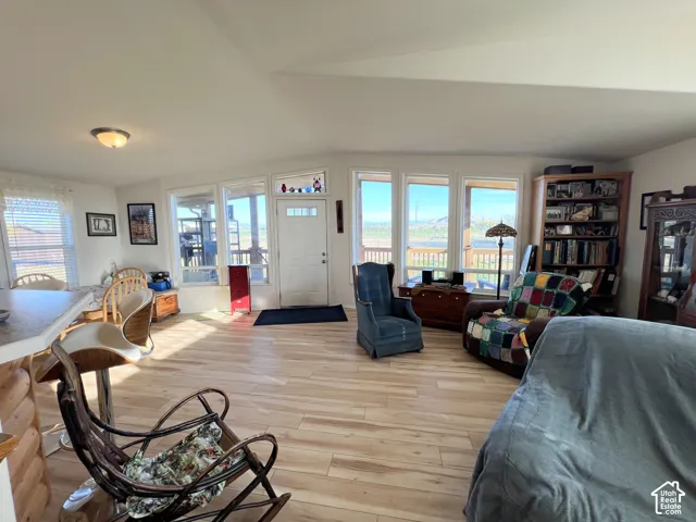 Expansive room featuring wood-finish flooring, multiple windows, a built-in bookshelf, and a kitchen counter with bar seating
