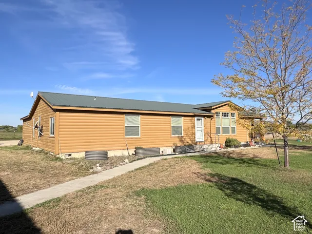Wood-look siding exterior with a dark-pitched roof and a concrete pathway leading to the entrance