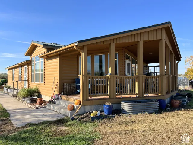 Expansive covered porch with wood railing and columns, horizontal siding, and multiple windows