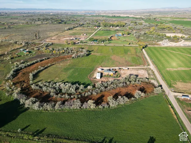 Expansive green fields, winding natural waterway, and distant mountain backdrop