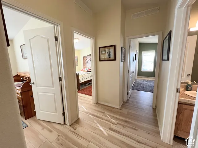 Wood-finish flooring throughout the hallway, leading to rooms with individual door access