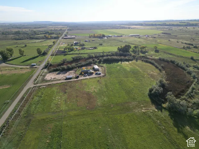 Expansive rural property featuring a winding waterway, a single-story residence, multiple outbuildings, and open grassy areas