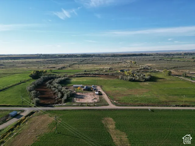 Expansive rural property with multiple structures, surrounded by agricultural fields and natural foliage