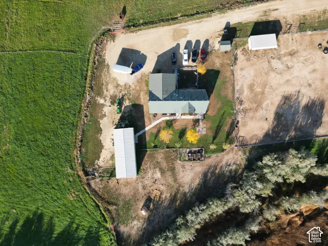 Property featuring a main residence with a green roof, multiple outbuildings, expansive land, and mature trees