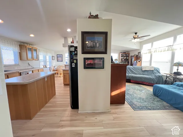 Open-concept living area featuring light wood-finish flooring, recessed lighting, a ceiling fan, and multiple windows