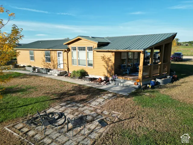 Exterior featuring wood-look siding, a covered porch with wood railings, a dark metal roof, and multiple windows
