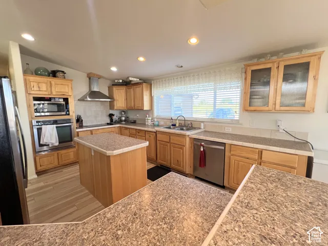 Kitchen featuring wood cabinetry, stainless steel appliances, a center island, and recessed lighting