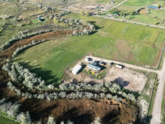 Expansive agricultural land featuring a residential structure, multiple outbuildings, and a surrounding natural landscape