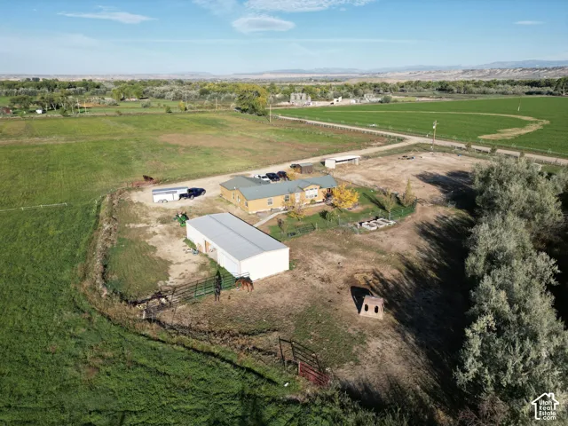 Expansive property featuring a central residence, large detached outbuilding, fenced grazing area, and substantial surrounding acreage