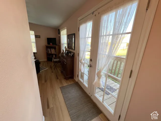 French doors with multiple panes of glass, wood-finish flooring, and a window with horizontal blinds