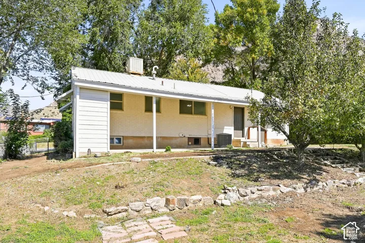 Single-story exterior with a metal roof, extended eaves, and an air conditioning unit