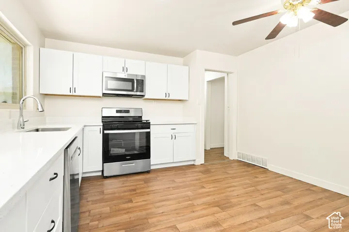 Updated kitchen featuring white cabinetry, stainless steel appliances, and white countertops