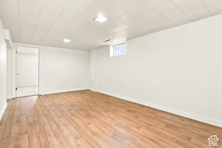 Wood-finish flooring, white paneled walls, recessed lighting, and a drop panel ceiling