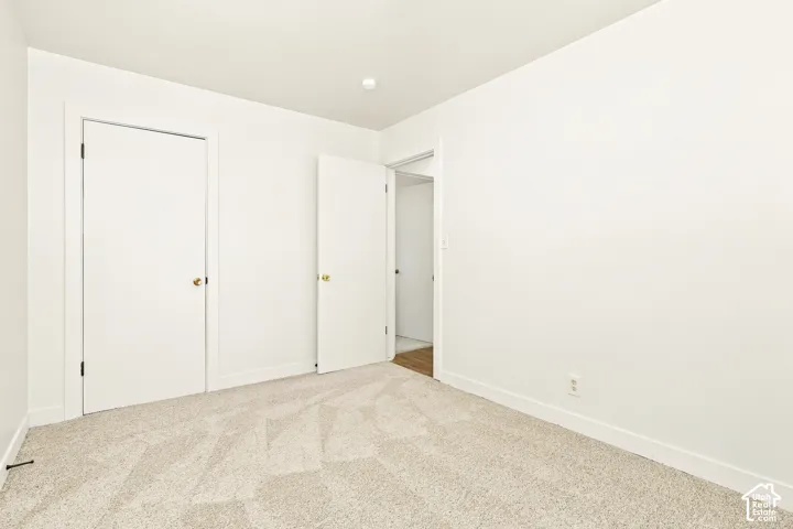Neutral-toned carpeting, white walls, and a recessed ceiling light create a bright atmosphere