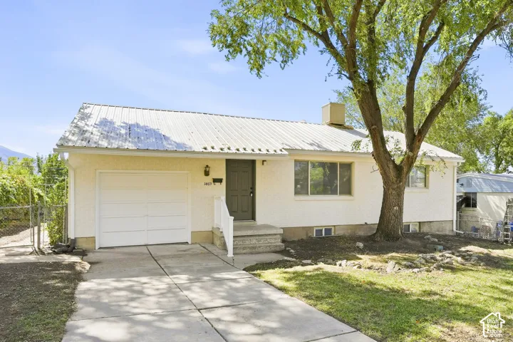 Single-story residence featuring a metal roof, attached single-car garage, and concrete driveway