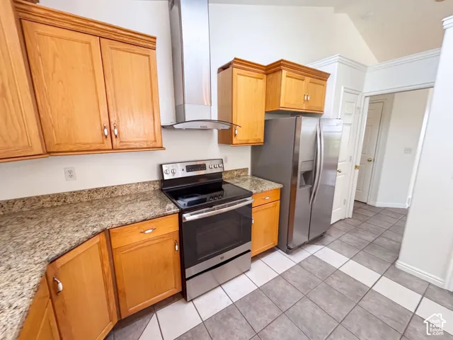 Stainless steel appliances, wood cabinetry, granite-finish countertops, cathedral ceiling, and tiled flooring