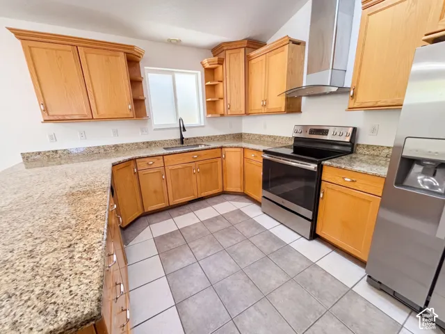 Kitchen featuring light wood cabinetry, stone-finish countertops, stainless steel appliances, and a tiled floor
