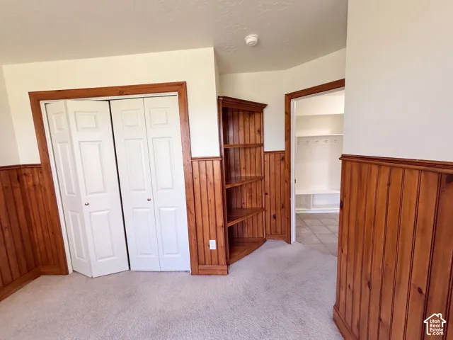 Warm wood paneling, corner built-in shelving, and light carpet flooring