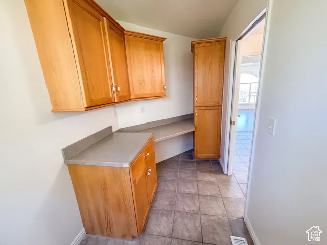 Wood-finish cabinetry with extensive storage, integrated desk space, and solid surface countertops