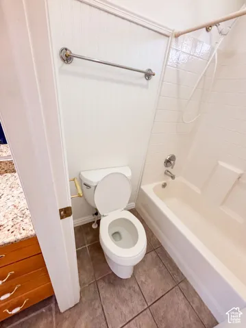 White beadboard paneling, ceramic tile flooring, and a shower-over-tub combination