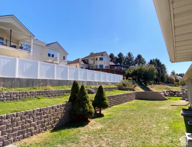 Expansive terraced backyard featuring a manicured lawn, multiple retaining walls, and established privacy fencing