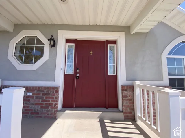 Red entry door with decorative glass sidelights, octagonal window, arched window, and brick facade accents