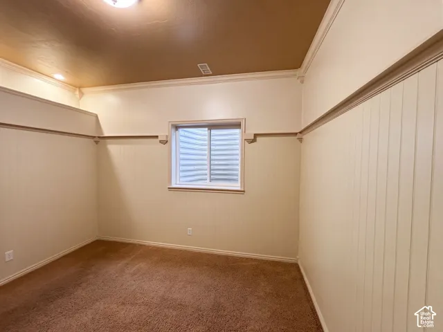 Textured wall paneling with crown molding, window with blinds, recessed lighting, and carpet flooring