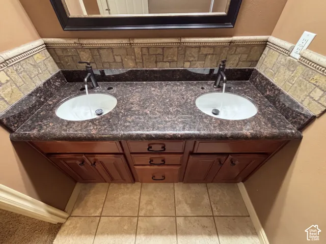 Double vanity with a dark speckled countertop, dual undermount sinks, and dark bronze-finish faucets