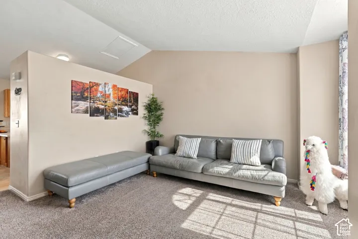 Vaulted ceiling with an attic access panel, neutral wall finishes, and wall-to-wall carpeting