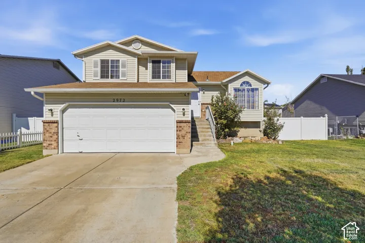Two-story residence featuring siding exterior, an integrated two-car garage, concrete driveway, and front lawn