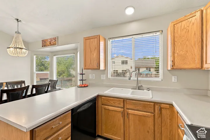 Kitchen featuring wood cabinetry, light-toned countertops, a double basin sink, and a built-in dishwasher