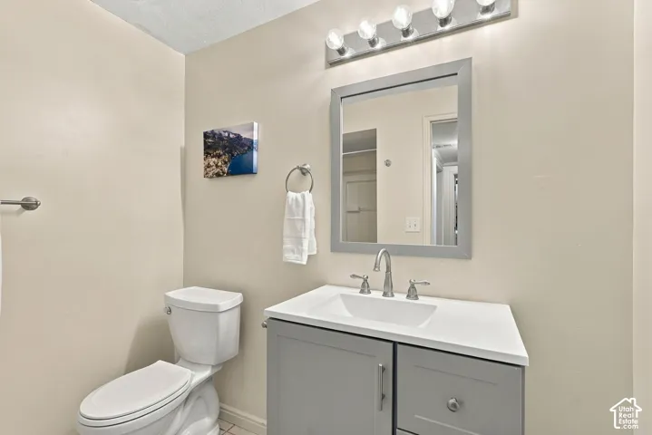 Vanity with gray cabinetry, white countertop, and chrome faucet