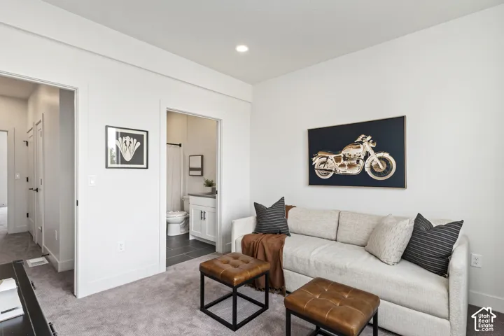Plush carpeted flooring with recessed lighting, white walls, and a bathroom entry featuring a vanity with a white countertop Pictures are of the model home