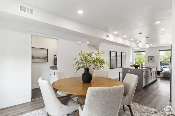 Recessed ceiling lighting, wood-finish flooring, white walls, and a visible kitchen island with pendant lighting Pictures are of the model home